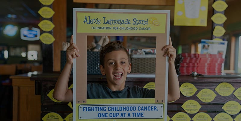 Alex's Lemonade Stand Foundation image with child holding up sign for Fighting Childhood Cancer