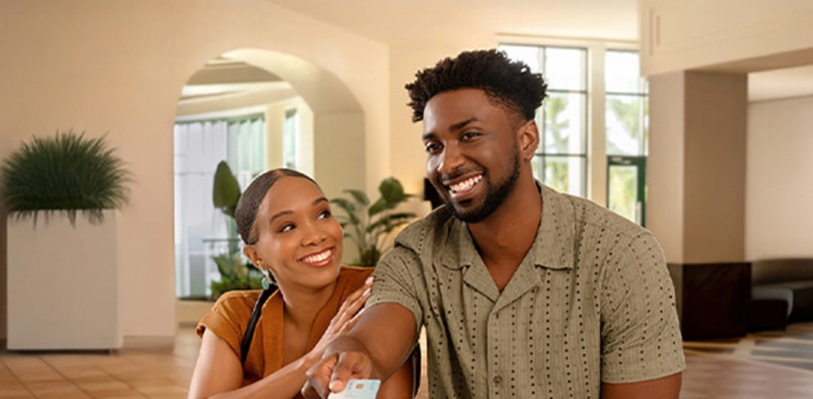 Image of a smiling couple at the reception desk presenting their card